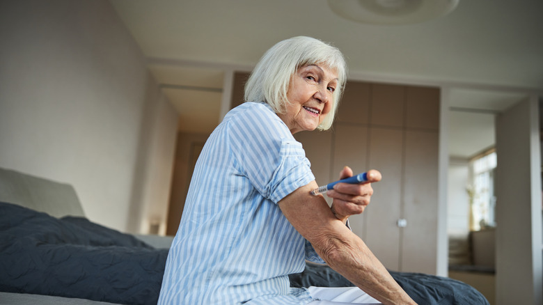 elderly woman giving herself injection in upper arm