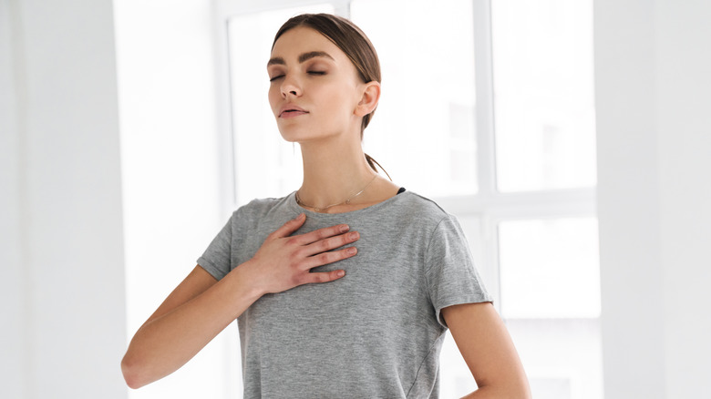 Woman performing breathing exercise indoors