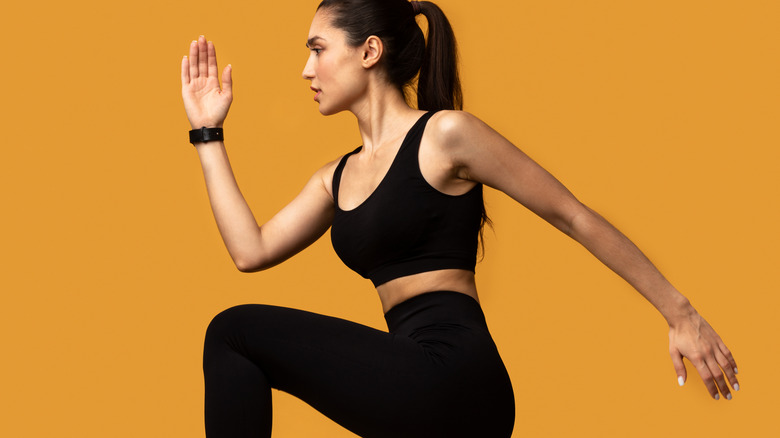 Woman performing knee raise yellow background