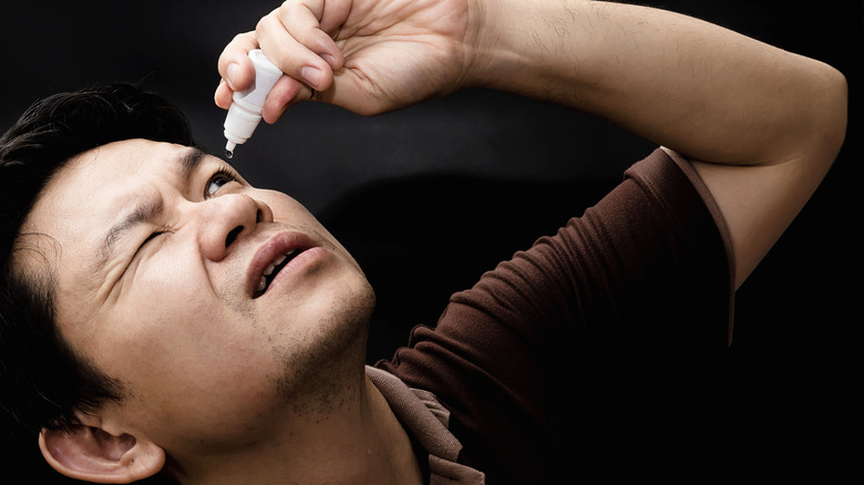 man using eye drops