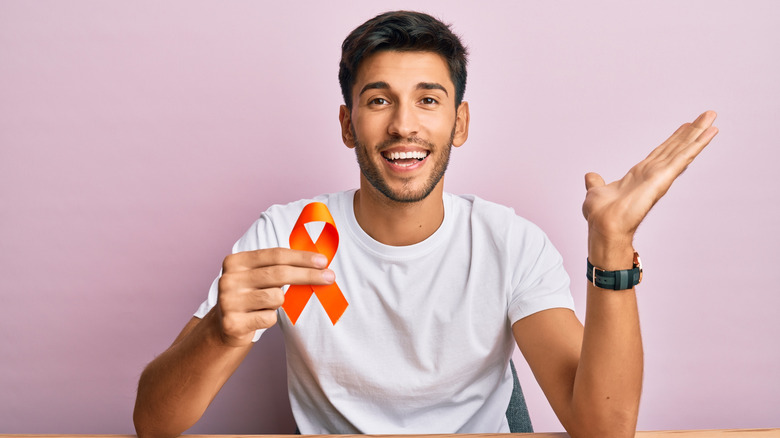 Smiling man holding orange ribbon