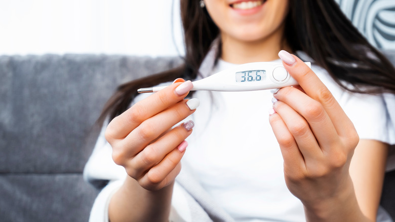 Smiling person holding body thermometer