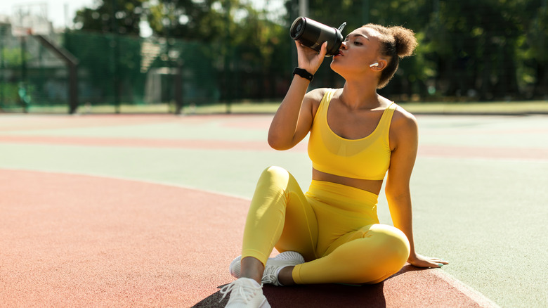 fit woman drinking a protein shake on a basketball court
