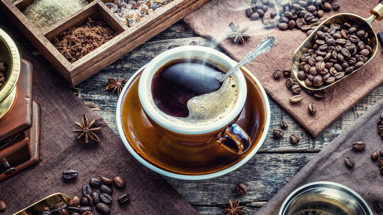 A cup of coffee surrounded by coffee beans