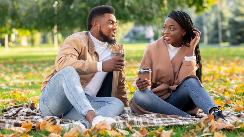 Couple holding coffee in park