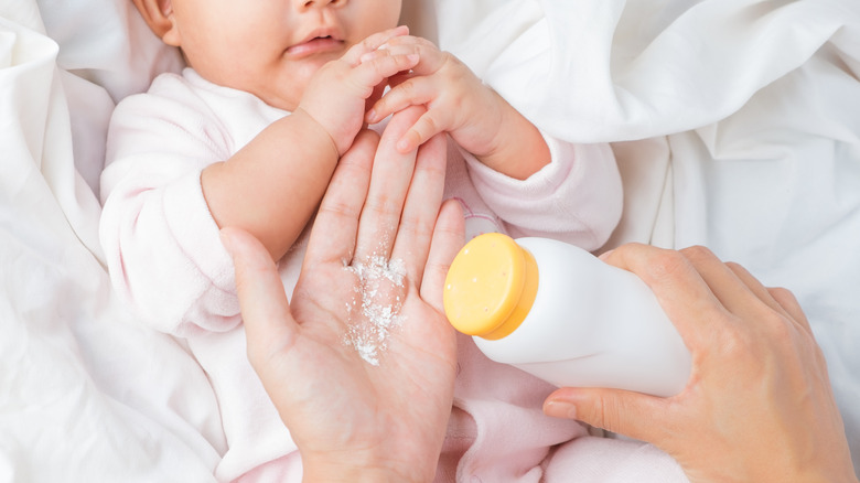 Woman preparing to put baby powder on infant