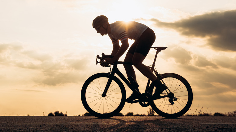 man cycling outdoors with the sun behind him