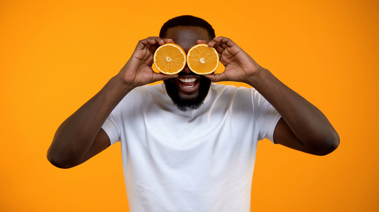 a man holds oranges up to his eyeballs 