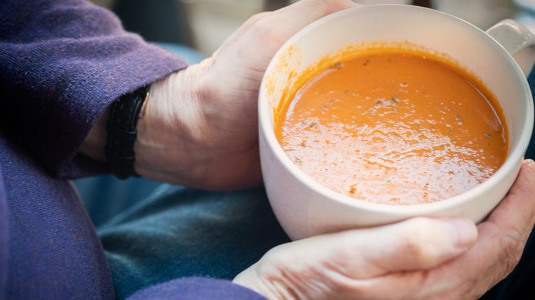 person holding a cup of tomato soup