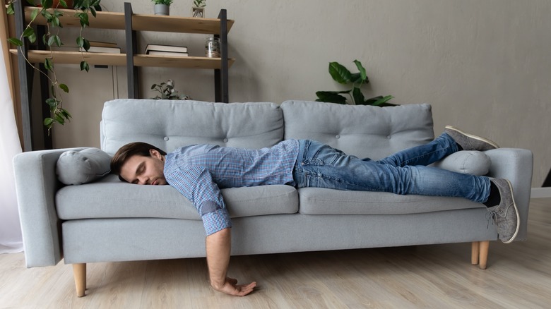 man lays on couch looking unwell