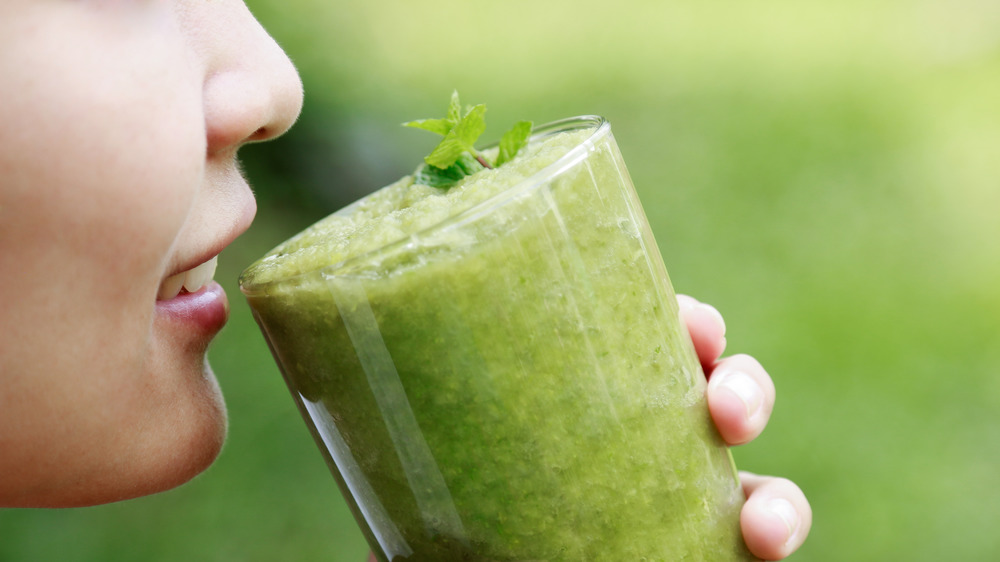 woman drinking glass of celery juice