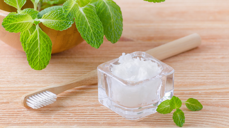 a tooth brush and small jar of coconut oil 