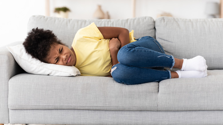 woman laying on couch with stomach ache