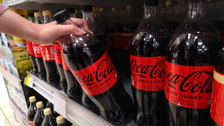 person taking coke zero from store shelf