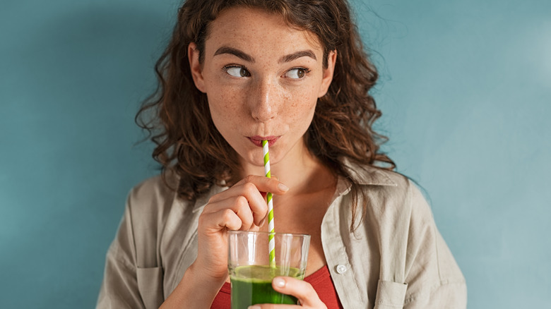 a girl drinking a green cold-pressed juice