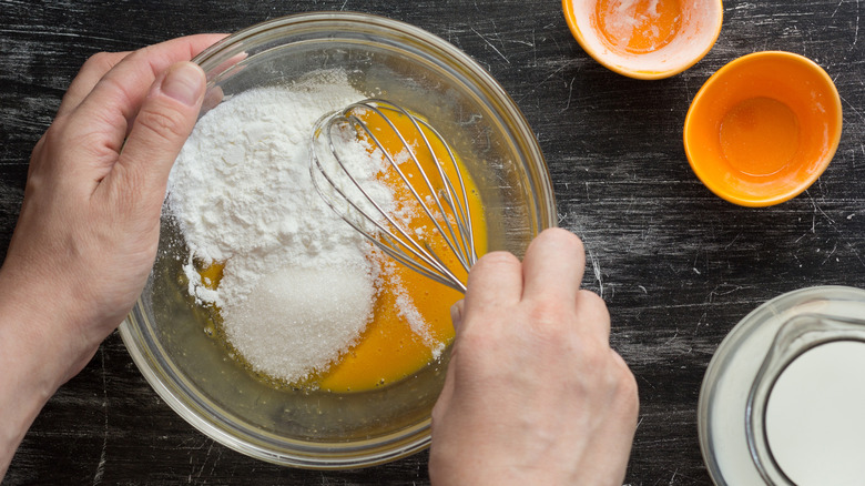 Woman mixing cornstarch, sugar, and eggs in a bowl