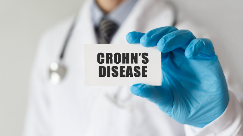 A doctor holding a card that says Crohn's disease