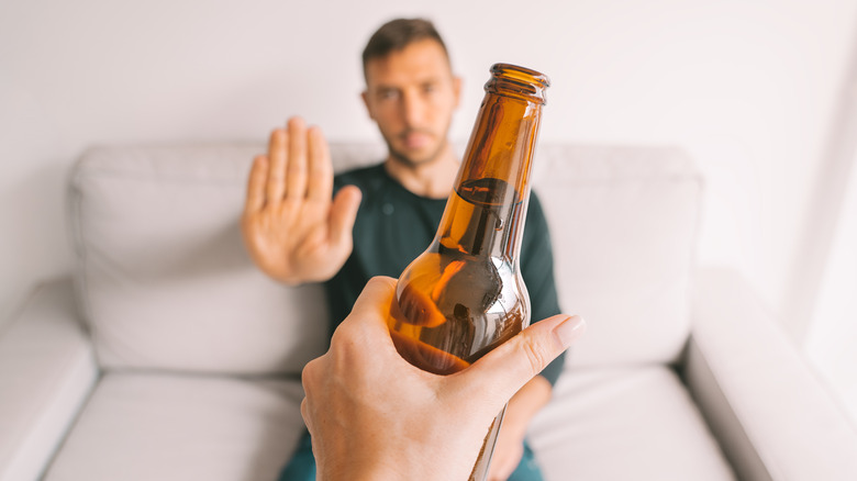 man refusing a bottle of beer