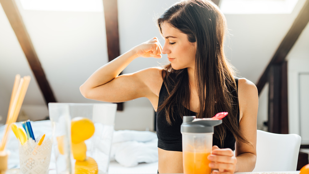 Woman drinking juice and flexing her bicep