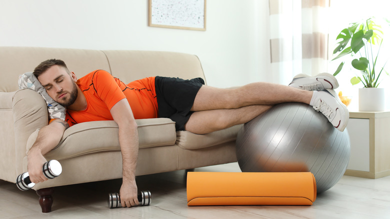 man resting on sofa with sports equipment