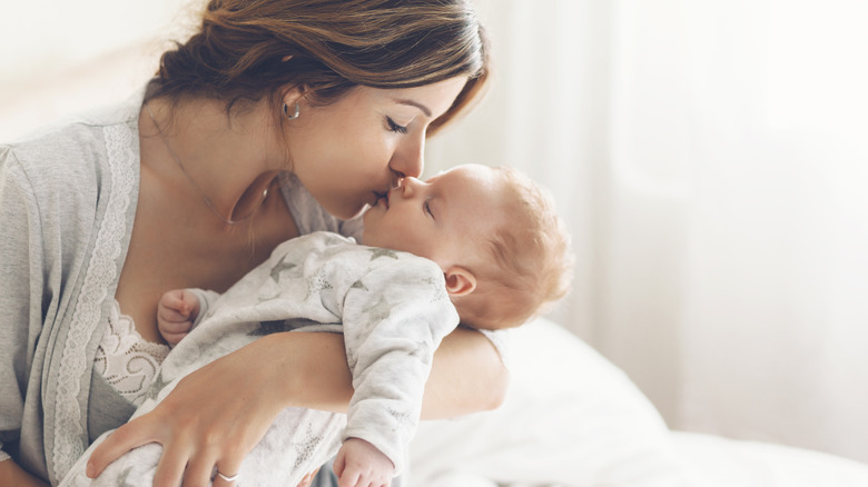 Mom holds and kisses baby on the lips 