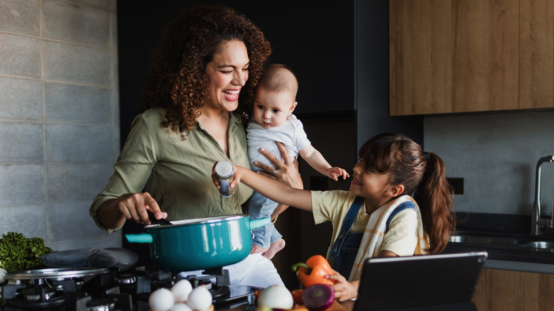 A mother with two children cooking inside the kitchen