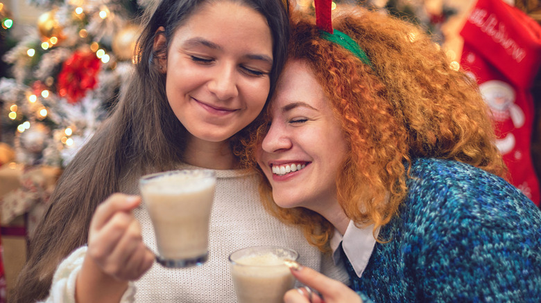 Two happy women holding glasses of eggnog