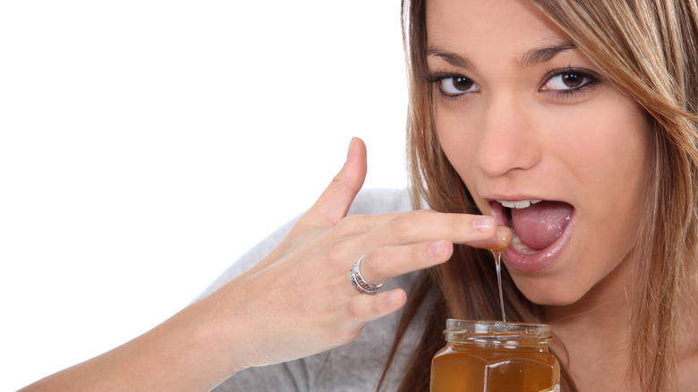 Woman eating honey from jar