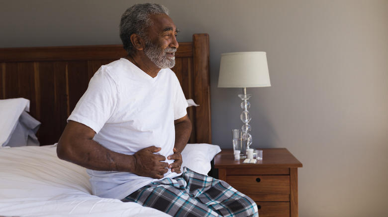 Man sitting up in bed holding his stomach