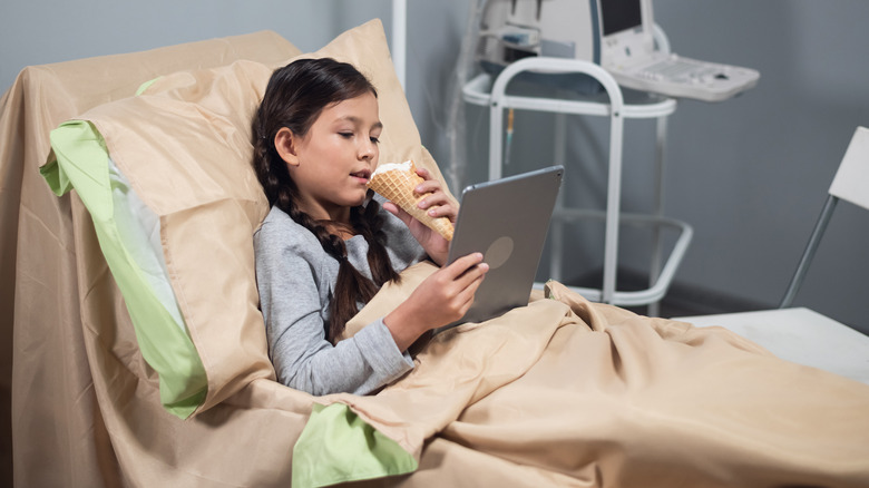 Young girl eating ice cream in hospital bed