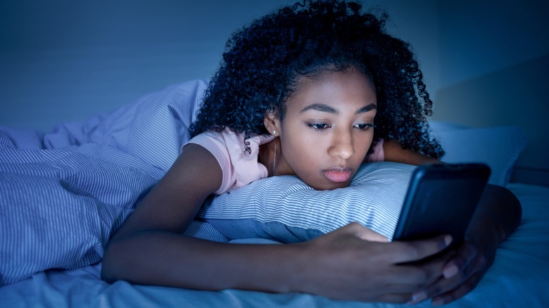 Young girl in bed with phone