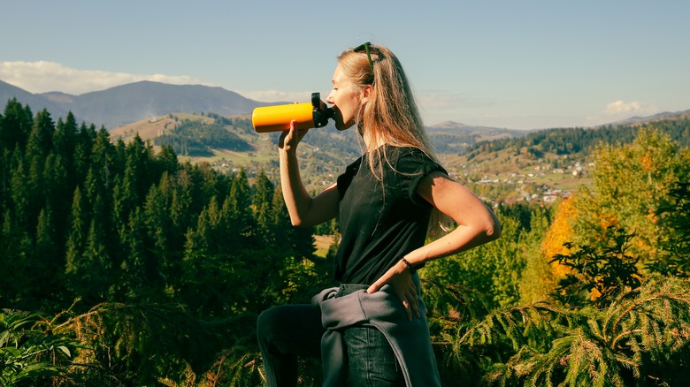 Blonde woman drinking on mountain