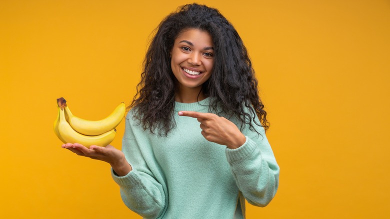 Smiling and pointing to a banana 