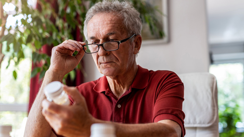older man checking pill bottle