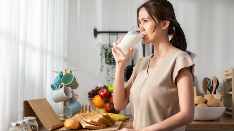 Woman drinking glass of milk in kitchen