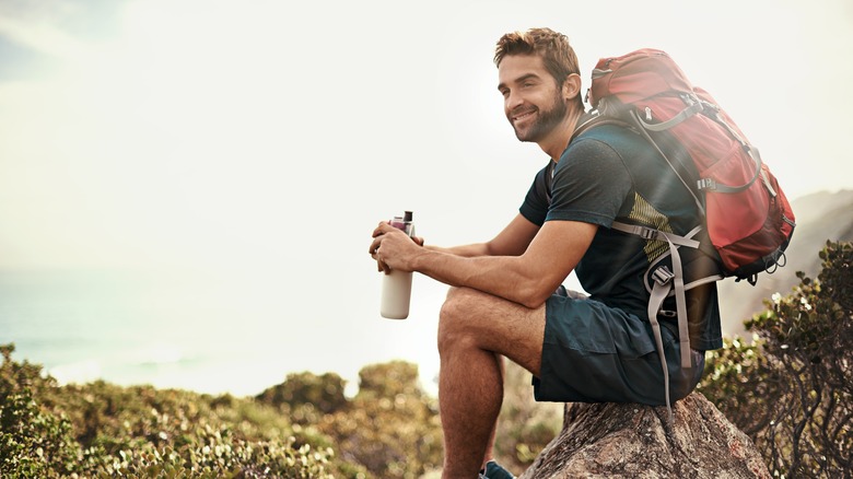 Young man drinking water while on a hike