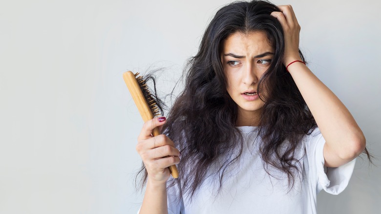 Woman brushing hair with hair falling out