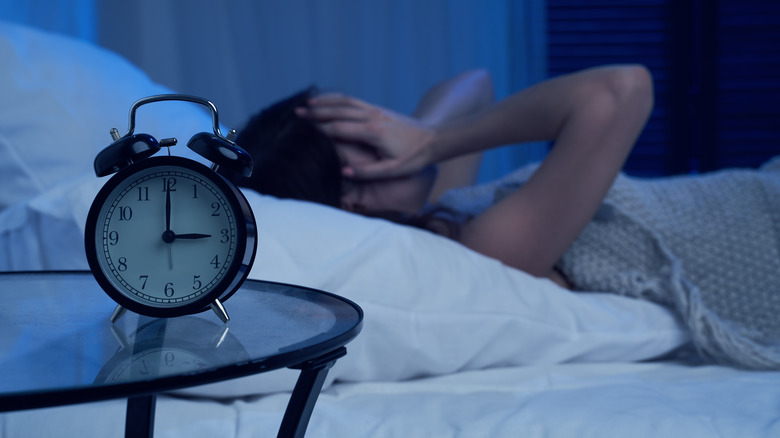 A woman laying awake at night and covering her face