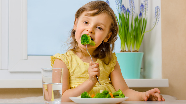 little girl eating broccoli