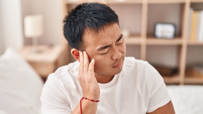 Young man holding ear in pain