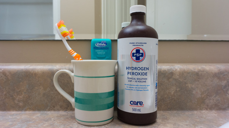 Toothbrush next to hydrogen peroxide bottle