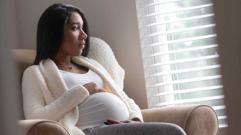 Pregnant woman sitting looking out window