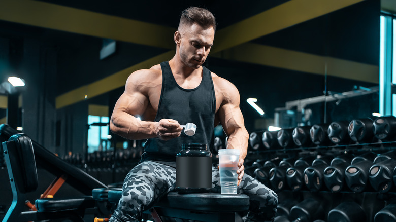 Muscular man mixing a protein shake at the gym