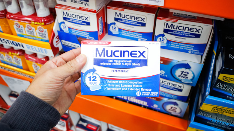 person holding a box of Mucinex