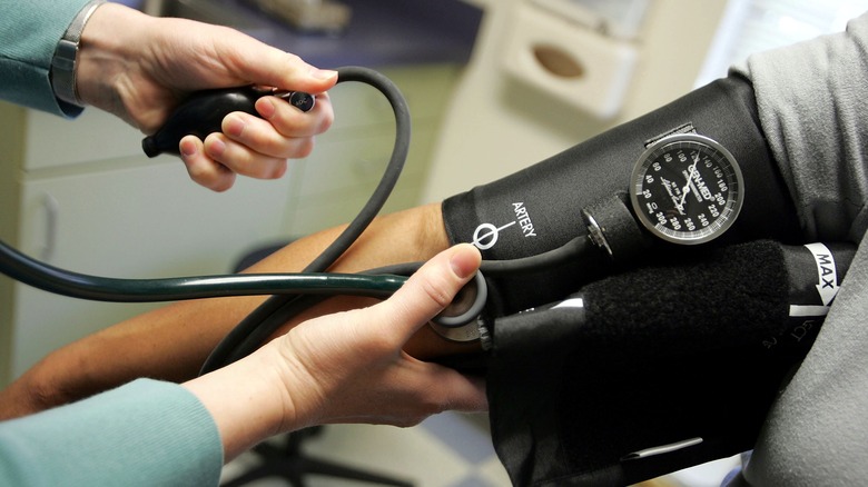 Medical professional takes blood pressure reading on patient using cuff