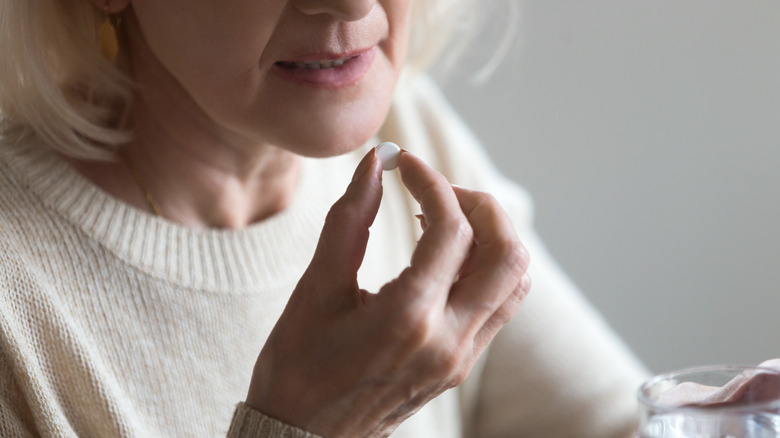 Older woman taking pill while holding water glass