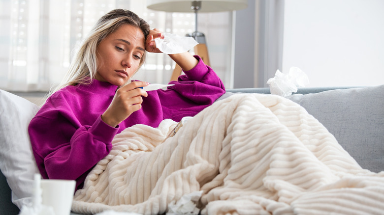 Sick woman under blanket on couch