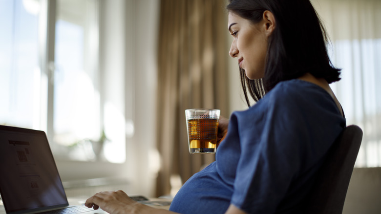 Pregnant woman working holding tea