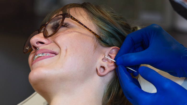 teenage girl getting her ear pierced