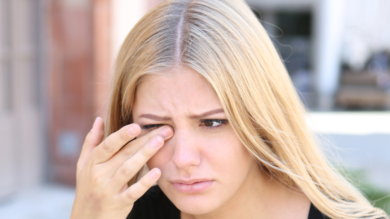 A woman in discomfort and rubbing her eye